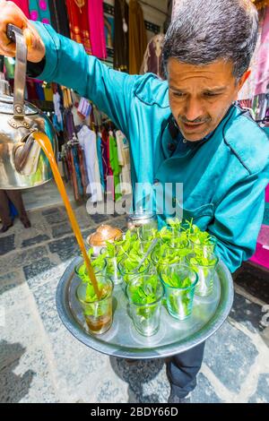 Homme qui verse du thé à la menthe à la médina. Banque D'Images