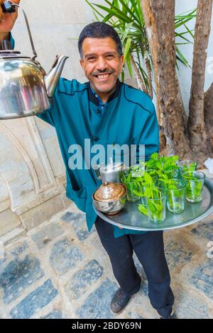 Homme qui verse du thé à la menthe à la médina. Banque D'Images