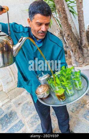 Homme qui verse du thé à la menthe à la médina. Banque D'Images