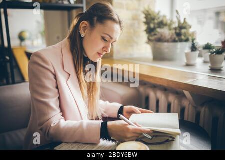 Travailler confortablement dans un café. Femme freelance feuilletant les pages d'un journal dans un café. Jolie femme à boire du café au restaurant Banque D'Images