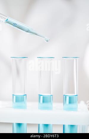 nettoyer les tubes en verre et les pipettes avec un réactif bleu clair pour le test du coronavirus Banque D'Images