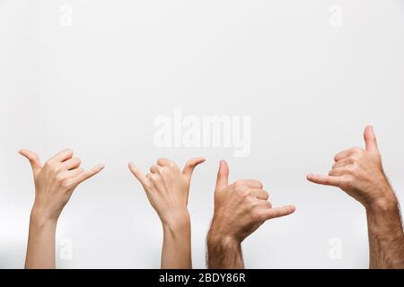 Gros plan photo des mains d'un homme et d'une femme isolée sur fond de mur blanc montrant un geste d'invitation à appeler plus tard. Banque D'Images