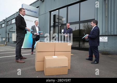 Le ministre de la Santé Robin Swann (à droite) aux côtés du ministre des Finances Conor Murphy (deuxième à droite) lors d'une visite à Huhtamaki dans l'Ouest de Belfast. Banque D'Images