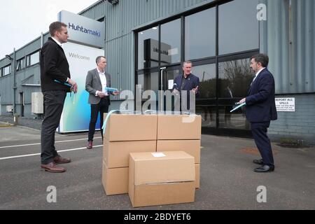 Le ministre de la Santé Robin Swann (à droite) aux côtés du ministre des Finances Conor Murphy (deuxième à droite) lors d'une visite à Huhtamaki dans l'Ouest de Belfast. Banque D'Images