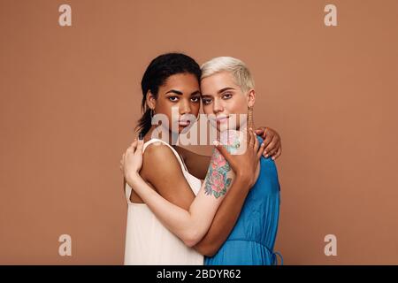 Deux belles femmes embrassant dans le studio. Femmes dans des robes regardant l'appareil photo. Banque D'Images