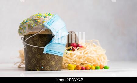 Gâteau de Pâques dans un masque de protection médical et des œufs au chocolat et lapin, gros plan. Protection contre les virus. Le concept de la célébration de Hol Banque D'Images