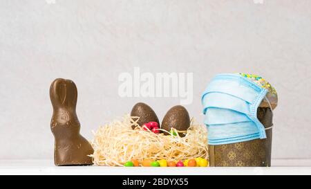 Gâteau de Pâques dans un masque de protection médical et des œufs au chocolat et lapin, gros plan. Protection contre les virus. Le concept de la célébration de Hol Banque D'Images