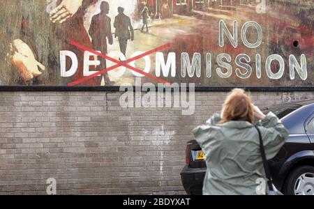 Un touriste photographie une vieille murale avec une déclaration qui se réfère à la question du déclassement des armes IRA est vu sur un mur à l'ouest de Belfast, en Irlande du Nord. La mise hors service de l'IRA a été confirmée. Un rapport du général John de Chastelain, chef de l'organe chargé de la surveillance du désarmement, confirmera que le déclassement de l'IRA sera achevé lundi aux gouvernements britannique et irlandais. Photo/Paul McErlane Banque D'Images