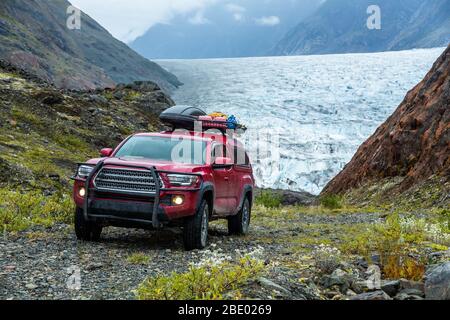 Camion de ramassage à quatre roues motrices rouge sur une route en gravier raide et étroite surplombant un glacier en Colombie-Britannique éloignée près du territoire du Yukon et de la région de l'Alaska Bo Banque D'Images