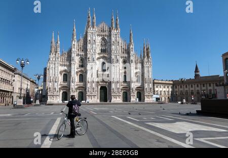 Vue sur la place déserte du Duomo à Milan, Italie pendant la pandémie de COVID-19 avec homme en vélo prenant la photo. Milano, ville italienne coronavirus quarantaine Banque D'Images