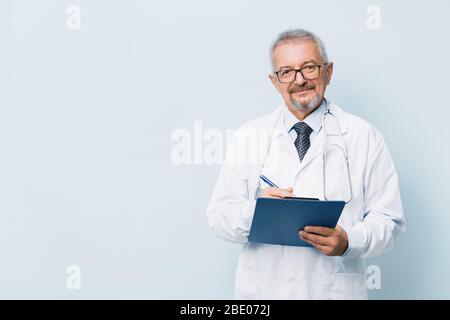 Médecin de sexe masculin âgé barbu en uniforme blanc avec stéthoscope avec dossier bleu. Médecin sur le fond d'un laboratoire de recherche médicale. Banque D'Images
