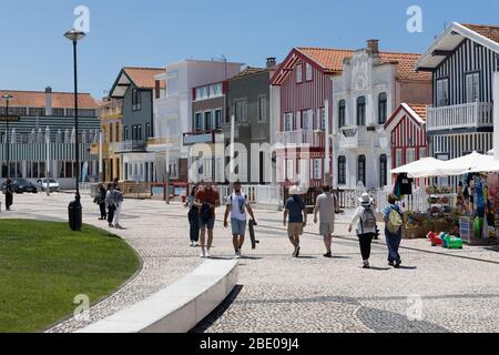 Les touristes marchant sur la promenade à travers des bâtiments colorés à rayures à Costa Nova do Prado Ilhavo près d'Aveiro Portugal. Banque D'Images