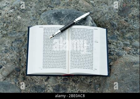 Bible hébraïque ouverte - TANAKH (Torah, Neviim, Ketuvim - la Loi, les prophètes, les écrits) avec plume de fontaine plein air. Isolé sur fond de pierres. Banque D'Images