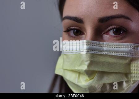 Femme de la santé portant un masque isolé sur fond gris. Espace pour la copie ou le texte. Port du stéthoscope et du manteau blanc. Banque D'Images