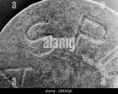 Micrographe électronique à balayage (SEM) d'une tablette d'aspirine. Les lettres « A S P » du mot aspirine sont visibles à la surface du comprimé. La photo montre que le comprimé apparemment lisse a une composition hétérogène. 60 x à 8 x 10'. Banque D'Images