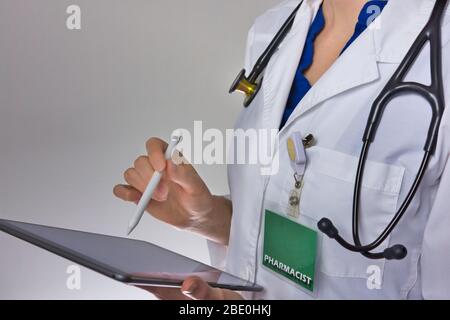 Pharmacien travaillant sur comprimé. Stéthoscope sur l'épaule, badge visible Banque D'Images