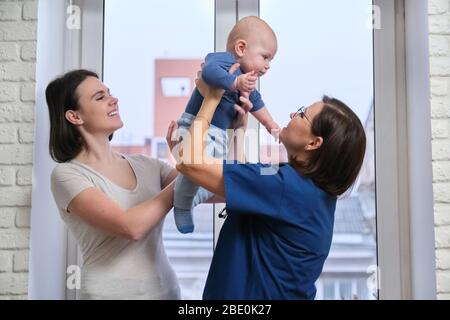 Médecin traitant des enfants en bas âge. La pédiatre prit bébé dans les bras, en parlant avec sa mère et en riant ensemble. Pédiatrie, soins et santé de c Banque D'Images