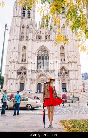 Fille avec un parapluie debout sur la place de l'homme ou Grand Platz à Bruxelles, Belgique avec une cathédrale derrière elle. Banque D'Images