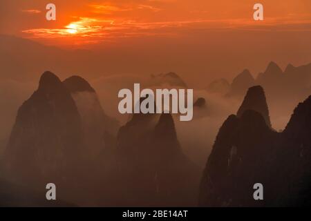 Le lever du soleil spectaculaire sur les pics de calcaire de Guilin enveloppés de brouillard. Banque D'Images