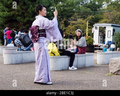 Kyoto, Japon - 30 septembre 2015 : jeune fille dans un kimono coloré prenant des photos avec smartphone dans le parc Maruyama Banque D'Images