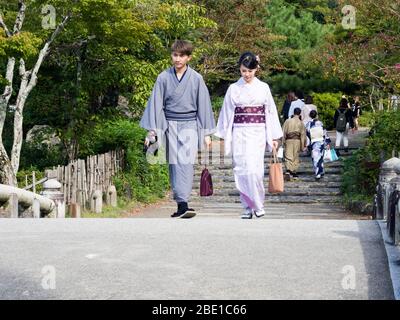 Kyoto, Japon - 30 septembre 2015 : un jeune couple de kimonos colorés marchant sur un pont en pierre dans le parc Maruyama Banque D'Images