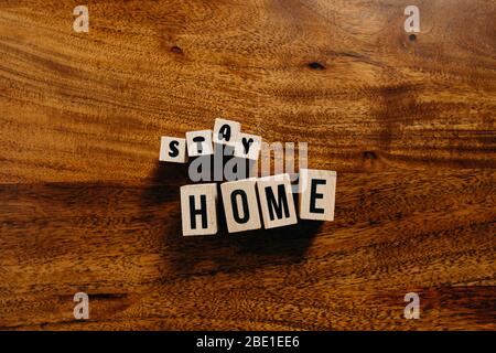 Texte « Stay home » en cube de bois sur fond de bois. Banque D'Images