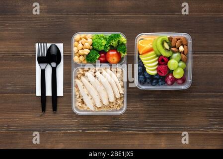 Vue de dessus de la nourriture saine riche en nutriments dans des boîtes à emporter avec cuillère et fourchette sur table en bois prête à manger Banque D'Images