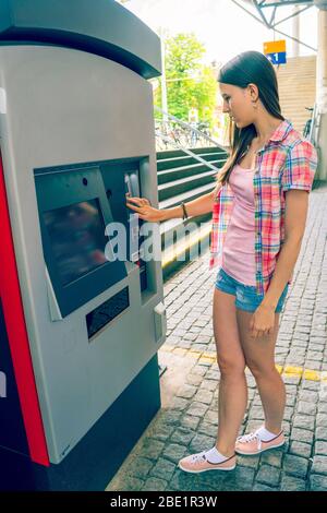 La jeune femme utilise un distributeur automatique pour les billets de transport Banque D'Images