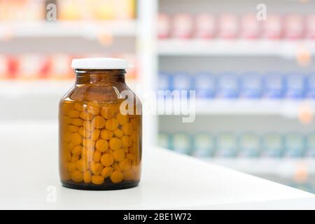 Petites pilules en flacon transparent de médecine ambrée à la table en pharmacie Banque D'Images