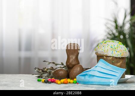 Gâteau de Pâques, masque de protection médical et œufs au chocolat et lapin, gros plan. Protection contre les virus. Le concept de la célébration du Saint Banque D'Images