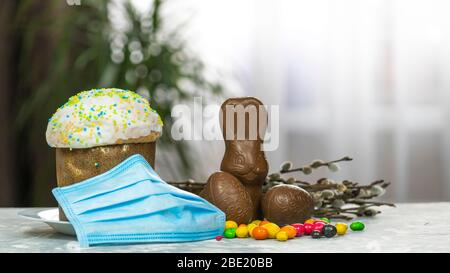 Gâteau de Pâques, masque de protection médical et œufs au chocolat et lapin, gros plan. Protection contre les virus. Le concept de la célébration du Saint Banque D'Images