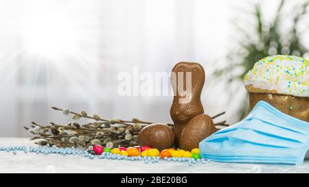 Gâteau de Pâques, masque de protection médical et œufs au chocolat et lapin, gros plan. Protection contre les virus. Le concept de la célébration du Saint Banque D'Images