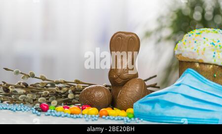 Gâteau de Pâques, masque de protection médical et œufs au chocolat et lapin, gros plan. Protection contre les virus. Le concept de la célébration du Saint Banque D'Images