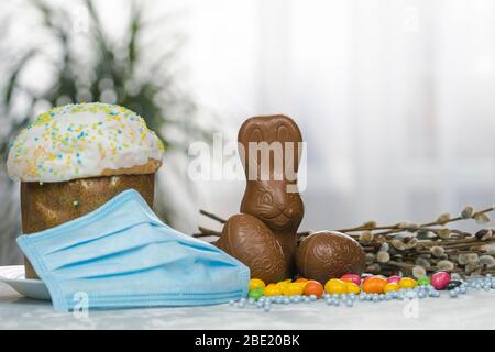 Gâteau de Pâques, masque de protection médical et œufs au chocolat et lapin, gros plan. Protection contre les virus. Le concept de la célébration du Saint Banque D'Images