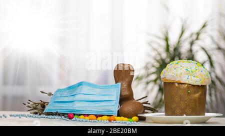 Gâteau de Pâques, masque de protection médical et œufs au chocolat et lapin, gros plan. Protection contre les virus. Le concept de la célébration du Saint Banque D'Images