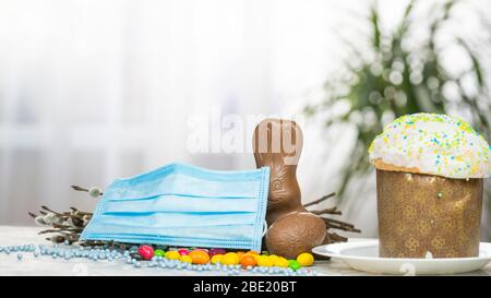 Gâteau de Pâques, masque de protection médical et œufs au chocolat et lapin, gros plan. Protection contre les virus. Le concept de la célébration du Saint Banque D'Images