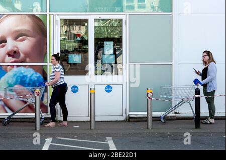 Brighton et Hove, Angleterre, avril 2020. à la suite de la pandémie de coronavirus, deux femmes gardent une distance sociale tout en faisant du shopping dans un supermarché. Banque D'Images