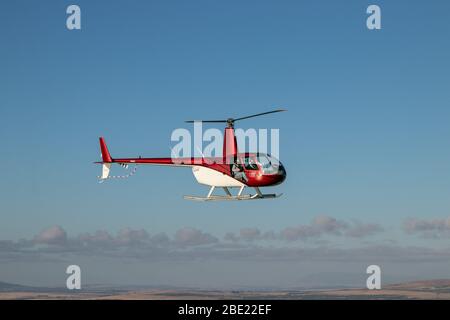 CAP, AFRIQUE DU SUD. Avril 2020. Un hélicoptère R-44 en rouge et blanc en vol au-dessus de cape Town. Banque D'Images