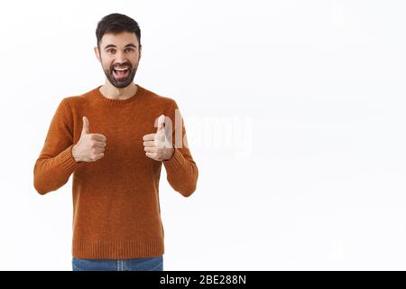 Très bien, continuez. Portrait de l'homme heureux et joyeux barbu montrer les pouces et sourire, approbation du signe de la tête, encourager la personne, se réjouir pour la réalisation Banque D'Images