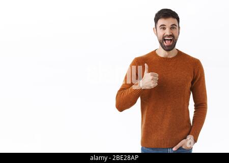 Portrait d'un homme bien-regardant enthousiaste barbu comme votre idée, montrer pouce et sourire heureux, satisfait avec un plan agréable, louent grand travail, donner Banque D'Images