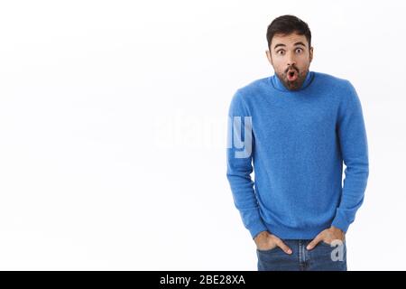 Portrait d'un homme choqué et étonné, surpris et affamé avec barbe, yeux craqués à l'appareil photo, bouche ouverte sans voix avec caméra à quelque chose Banque D'Images