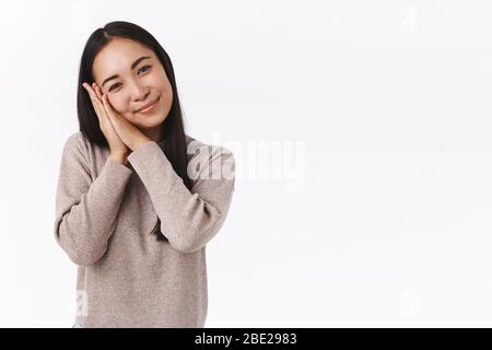 Tendre une charmante femme asiatique aux cheveux sombres en hiver, incliner la tête en soie et mignon, se pencher sur les palmiers et contempler quelque chose de charmant avec Banque D'Images