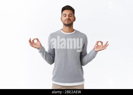 Patient attentif et jeune homme détendu heureux, exercices de respiration, tenir les mains sur les côtés et sourire soulagé, relâcher le stress pendant le temps de travail Banque D'Images