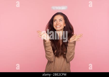 Portrait de la jeune femme charmante et ludique avec halo au-dessus de la tête levant les mains dans le bewilderment, gesturant je ne sais pas, regardant vers le haut et souriant confus Banque D'Images