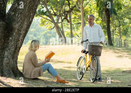 Aimez couple se détendre en vélo et lire livre dans le parc Banque D'Images