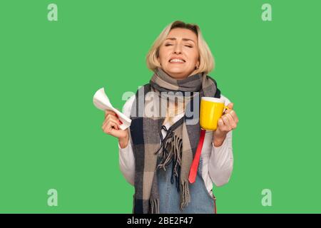Je déteste avoir la grippe! Portrait d'une femme adulte irritée enveloppée dans un foulard tenant le thé, la serviette et les dents de claçage avec la colère, se sentant désespérée au sujet de l'influ Banque D'Images