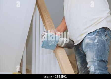 Un escalier en bois rénovation railing papier de verre ponçage pour mains courantes en bois Banque D'Images