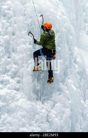 Grimpeur de glace utilisant des pipes de glace et des crampons pour grimper une chute d'eau gelée dans le canyon Maligne, parc national Jasper, Alberta, Canada Banque D'Images