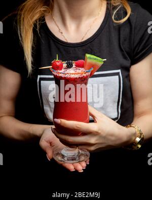 femme tenant un verre de cocktail de fruits garni de framboises et de pastèques à la fraise Banque D'Images