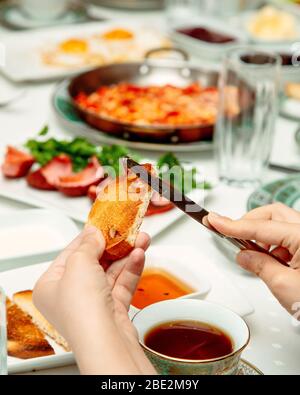 femme qui répand du miel sur toast et qui a du thé noir Banque D'Images
